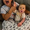 children, sibling, baby, toddler, infant, sister, smiling, yawning, pacifier, couch, cushion, blanket, whale_pattern, indoor, portrait, sitting, family, casual_clothing, happy, home