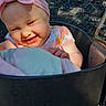 baby, child, infant, smiling, laughing, face, portrait, pink_bow, headband, floral_clothing, stroller, outdoor, sunlight, seated, blanket, happy, close_up, baby_carriage, black_tray, playful