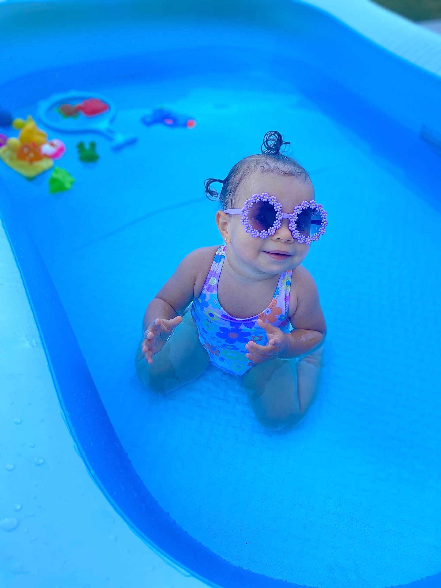 Ariah participe au concours pour gagner de l'argent avec cette photo : toddler, child, pool, water, sunglasses, swimsuit, toys, summer, outdoor, playful, happy, fun, blue, plastic_pool, sitting, water_toys, cute, hair_buns, small_pool, sunshine