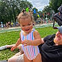 toddler, child, adult, swimsuit, grass, picnic_blanket, park, water_fountain, splash_park, trees, outdoor, sunny, playing, summer, smiling, happy, people, water_spray, colorful, recreation