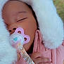 baby, sleeping, pacifier, pink_jacket, fluffy_hood, hand, red_nail_polish, close_up, outdoor, green_background, peaceful, child, infant, cozy, cute, portrait, warm_clothing, toddler, face, soft