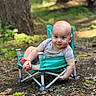 baby, child, outdoor, forest, camping_chair, smile, cute, nature, greenery, dirt, leaves, sunlight, playful, infant, sitting, small_chair, happy, barefoot, casual_clothing, daylight