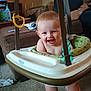 baby, smiling, baby_jumper, indoor, living_room, furniture, couch, carpet, toy, child, happy, seat, person, home, playtime, infant, strap, plastic, green, blue