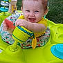 Jaxson joined the competition — help win amazing prizes! baby, child, smiling, toy, baby_walker, outdoor, grass, fence, yellow_clothing, happy, cute, playtime, infant, person, portrait, colorful, sunlight, fun, hand, seat
