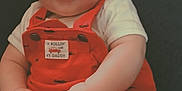 Jaxson joined the competition — help win amazing prizes! baby, child, smile, red_overalls, white_shirt, sitting, hands, face, cute, infant, happy, chubby, clothing, portrait, indoors, young_child, person, head, background, seated