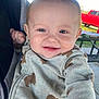 baby, smiling, child, fleece, bear_pattern, cozy, outdoor, picnic_table, red_truck, person, face, happy, clothing, hand, daylight, cheerful, head, sitting, casual, infant