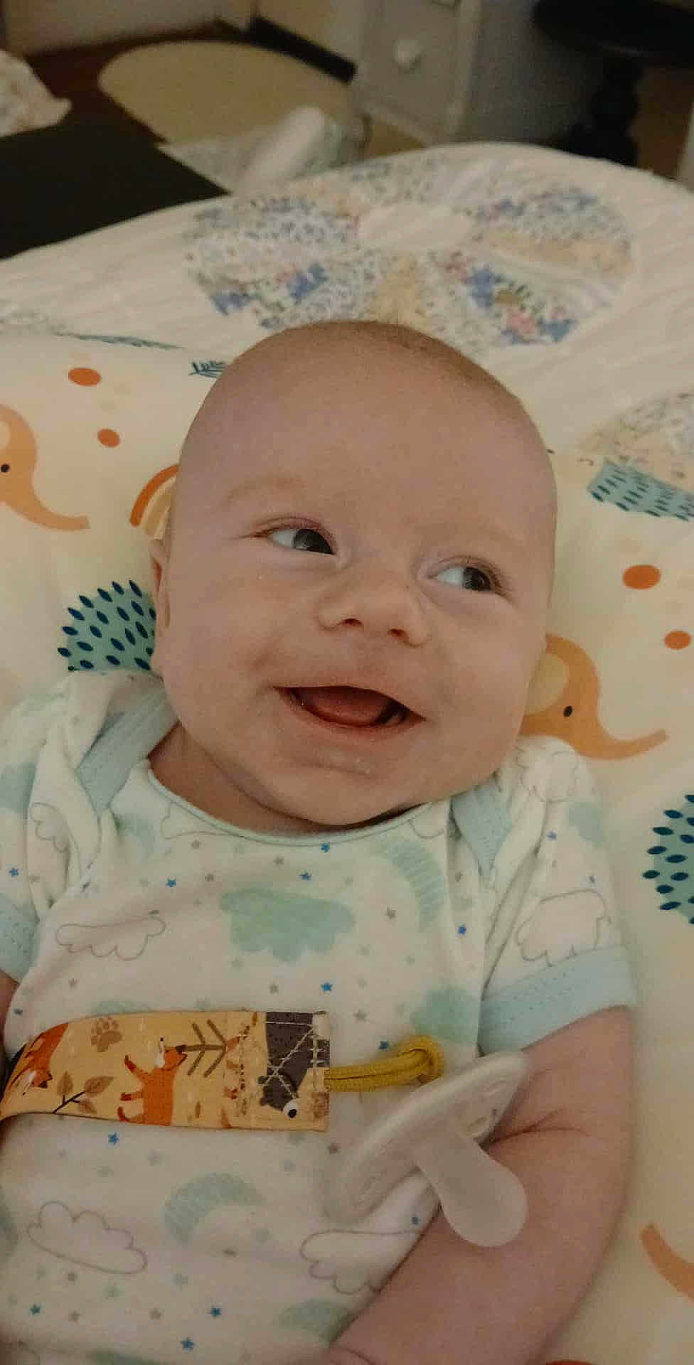 Sawyer joined the competition — help win amazing prizes! baby, smiling, pacifier, infant, cute, bed, pillow, patterned, clothing, happy, child, lying_down, indoor, soft, comfort, young, face, skin, person, expression