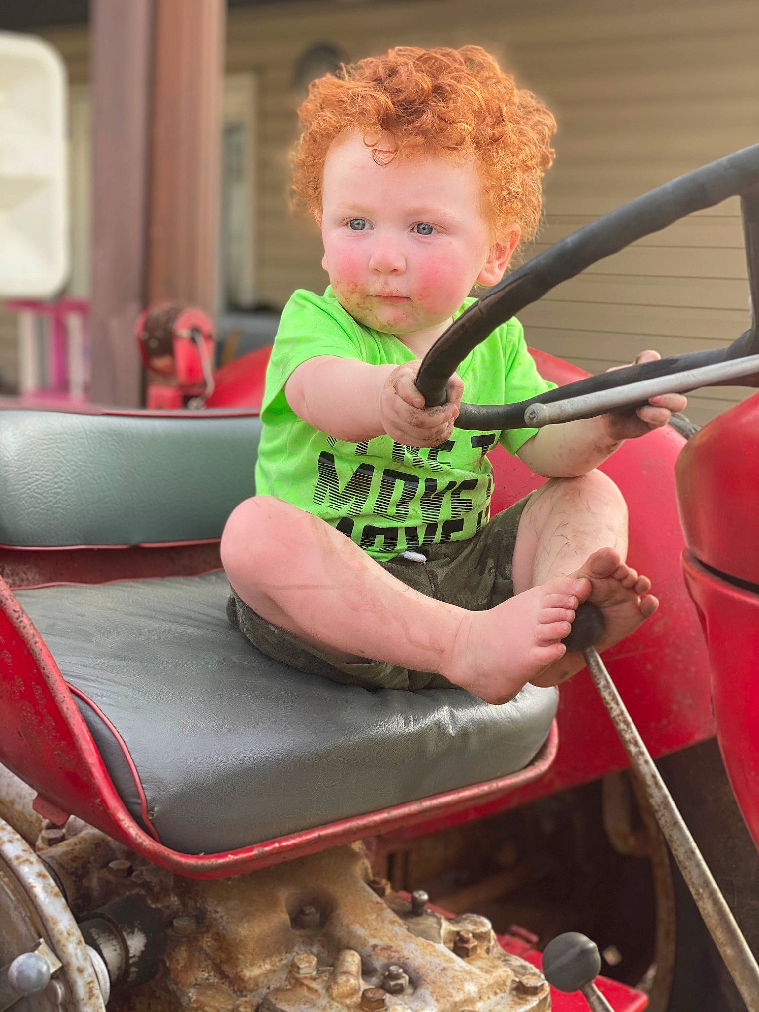 Travis is registered to the contest to win money with this photo: arm, automotive_exterior, automotive_tire, baby, eye, fun, grass, hair, head, hood, human_body, leisure, motor_vehicle, person, recreation, steering_wheel, toddler, vehicle, vehicle_door, windscreen_wiper