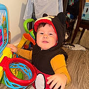 Gabriel García joined the competition — help win amazing prizes! toddler, child, indoor, toy, basketball_hoop, hoodie, mickey_mouse, floor, clothing, hand, face, smile, curious, play, furniture, chair, basketball, wood_floor, person, room