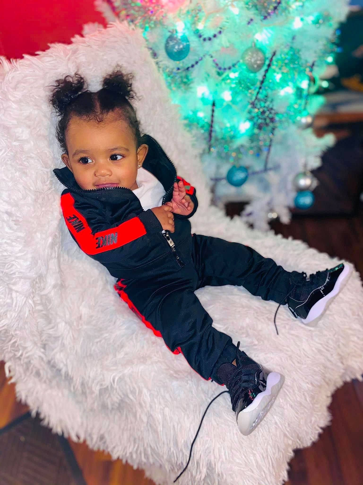 Dakari is registered to the contest to win money with this photo: baby, baby_toddler_clothing, child, christmas_ornament, christmas_tree, costume_hat, event, eye, fun, fur_clothing, glove, happy, hat, head, headgear, human_body, person, standing, toddler, tree