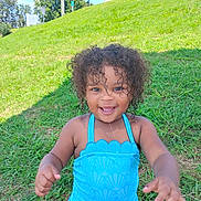 Bessie joined the competition — help win amazing prizes! child, toddler, curly_hair, blue_swimsuit, grass, outdoor, smiling, happy, summer, sunny, nature, playful, person, young_child, greenery, daylight, cute, portrait, fun, casual