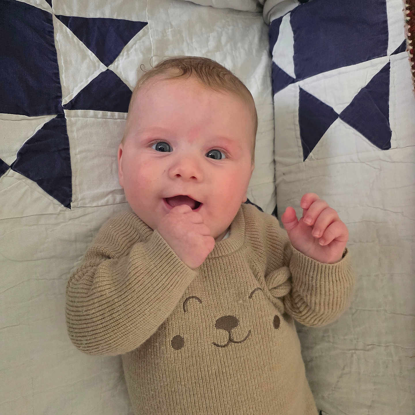 Mikhael participe au concours pour gagner de l'argent avec cette photo : baby, infant, smiling, sweater, knitwear, quilt, blanket, face, hand, blue, white, pattern, cute, child, portrait, lying_down, happy, indoors, person, apparel