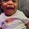 baby, smiling, happy, infant, face, expression, clothing, white_shirt, palm_tree, sunset, text_on_clothing, cute, portrait, indoor, child, young, joyful, closeup, person, background