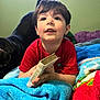 Killian joined the competition — help win amazing prizes! child, boy, book, holy_bible, blanket, colorful_blanket, red_shirt, dog, pet, indoor, portrait, face, smiling, curious, bed, resting, hand, hair, eyes, cozy