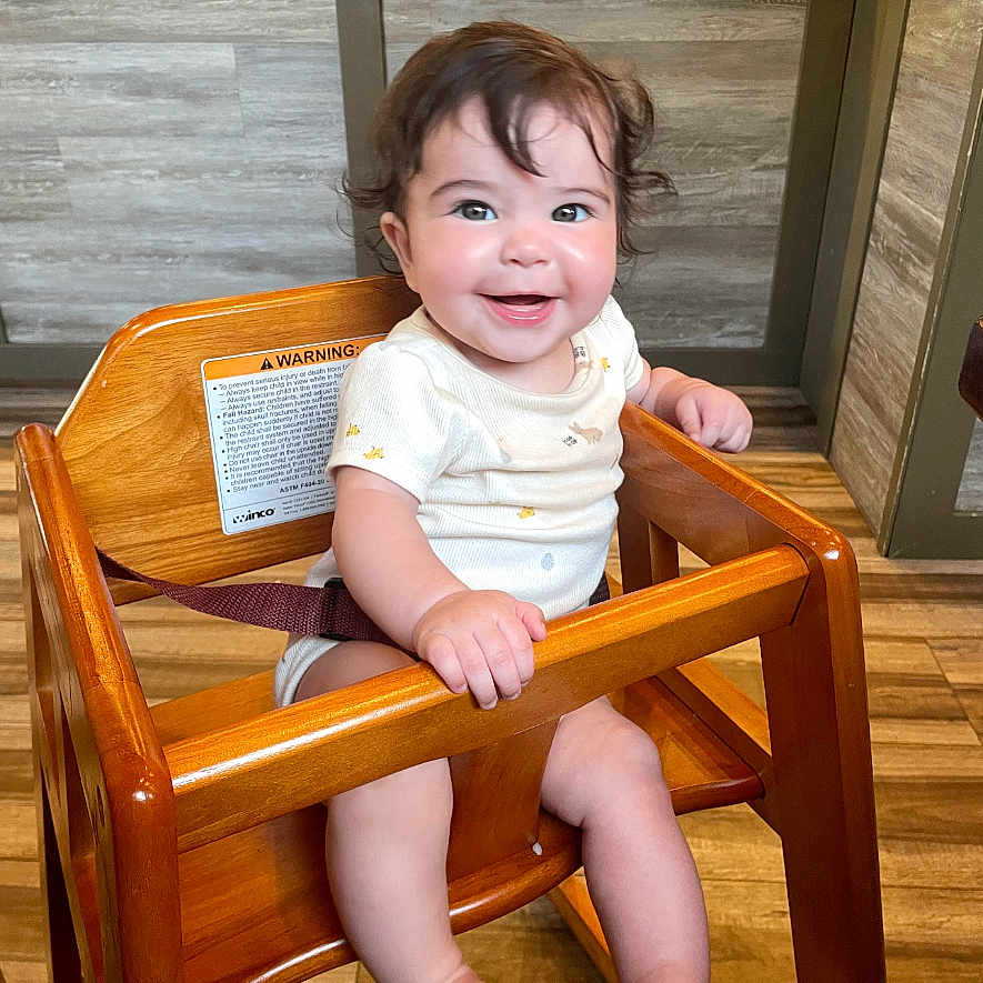 Azarah joined the competition — help win amazing prizes! baby, bright, child, clothing, cute, eyes, face, flooring, hair, hand, happy, high_chair, indoor, infant, person, short_sleeves, sitting, smile, wood, wooden_furniture