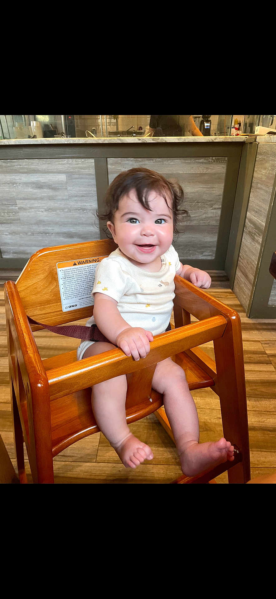Azarah joined the competition — help win amazing prizes! baby, high_chair, smile, wooden_furniture, indoor, child, happy, infant, person, flooring, wood, face, sitting, cute, short_sleeves, clothing, bright, eyes, hair, hand