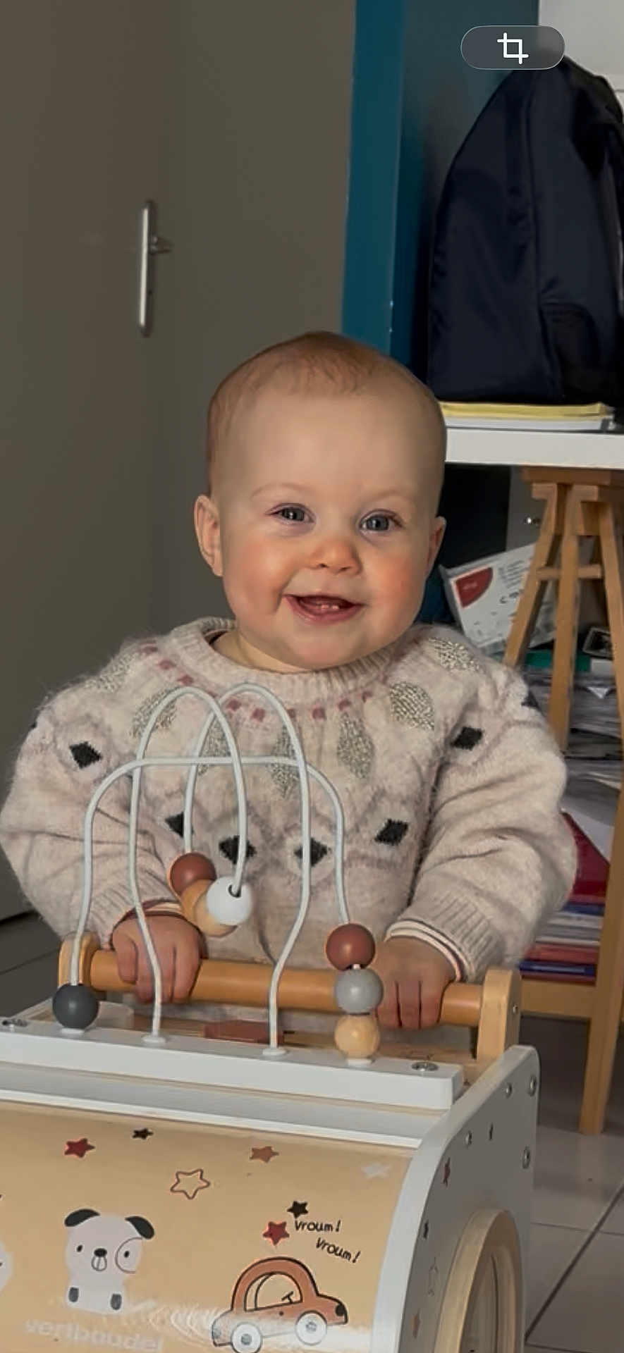 Léa participe au concours pour gagner de l'argent avec cette photo : baby, child, toy, wooden_toy, bead_maze, sweater, indoor, smiling, face, hands, furniture, backpack, papers, floor, person, cute, playing, happy, home, infant