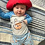 Kane joined the competition — help win amazing prizes! baby, red_hat, blue_shirt, striped_blanket, cute, infant, smiling, lying_down, child, face, portrait, clothing, patterned_shorts, indoors, soft_texture, happy, small_feet, person, headwear, playful