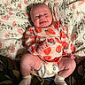 baby, infant, smiling, lying_down, blanket, floral_pattern, clothing, diaper, socks, happy, cute, child, person, indoors, soft_lighting, portrait, hands, legs, face, cozy