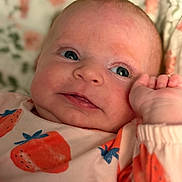 Anora is registered to the contest to win money with this photo: baby, infant, face, eyes, hand, clothing, pattern, strawberry, pink, skin, portrait, cute, child, newborn, expression, lying_down, soft_light, background, floral, closeup