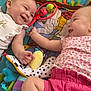 baby, infant, smiling, playmat, toy, plush_toy, colorful, child, cute, happy, lying_down, interaction, toddler, clothing, pink_shorts, white_shirt, patterned_top, blocks, soft_toys, indoors