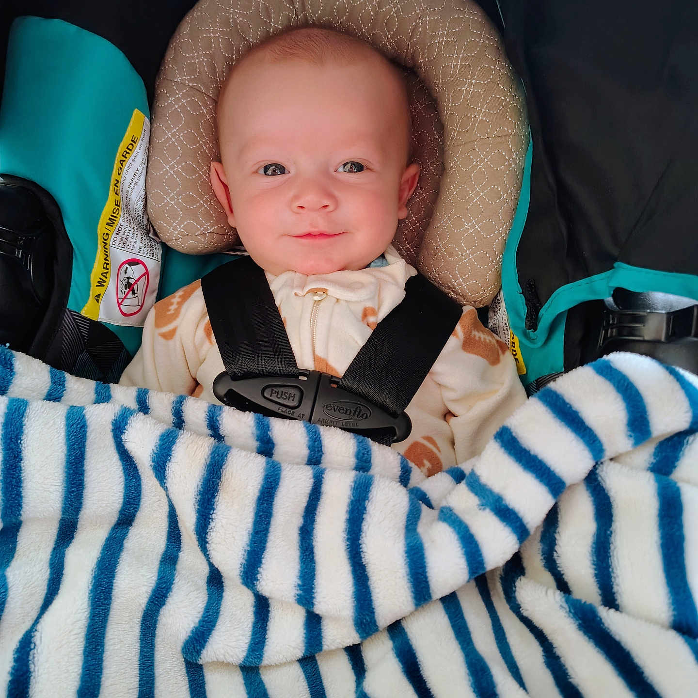 Cayden is registered to the contest to win money with this photo: baby, blanket, blue, buckle, car_seat, child, cozy, cute, eyes, fabric, headrest, hood, infant, onesie, pillow, portrait, seatbelt, smile, stripes, white