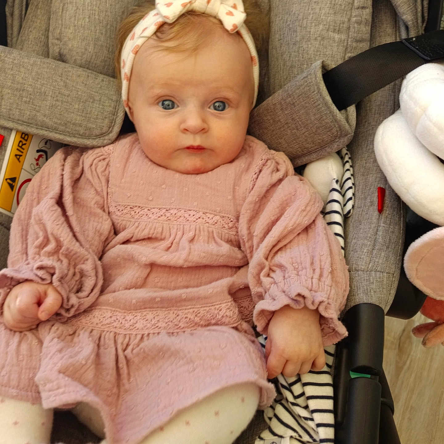 Iris participe au concours pour gagner de l'argent avec cette photo : baby, infant, child, pink_dress, headband, stroller, blanket, curious, wide_eyes, cute, baby_gear, seated, indoors, soft_lighting, clothing, person, portrait, baby_fashion, headwear, toddler