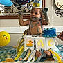 James joined the competition — help win amazing prizes! baby, balloon, banner, birthday, blue_frosting, cake, celebration, child, crown, decorations, face, feet, hand, highchair, indoor, messy, party, smiling, suspenders, tablecloth