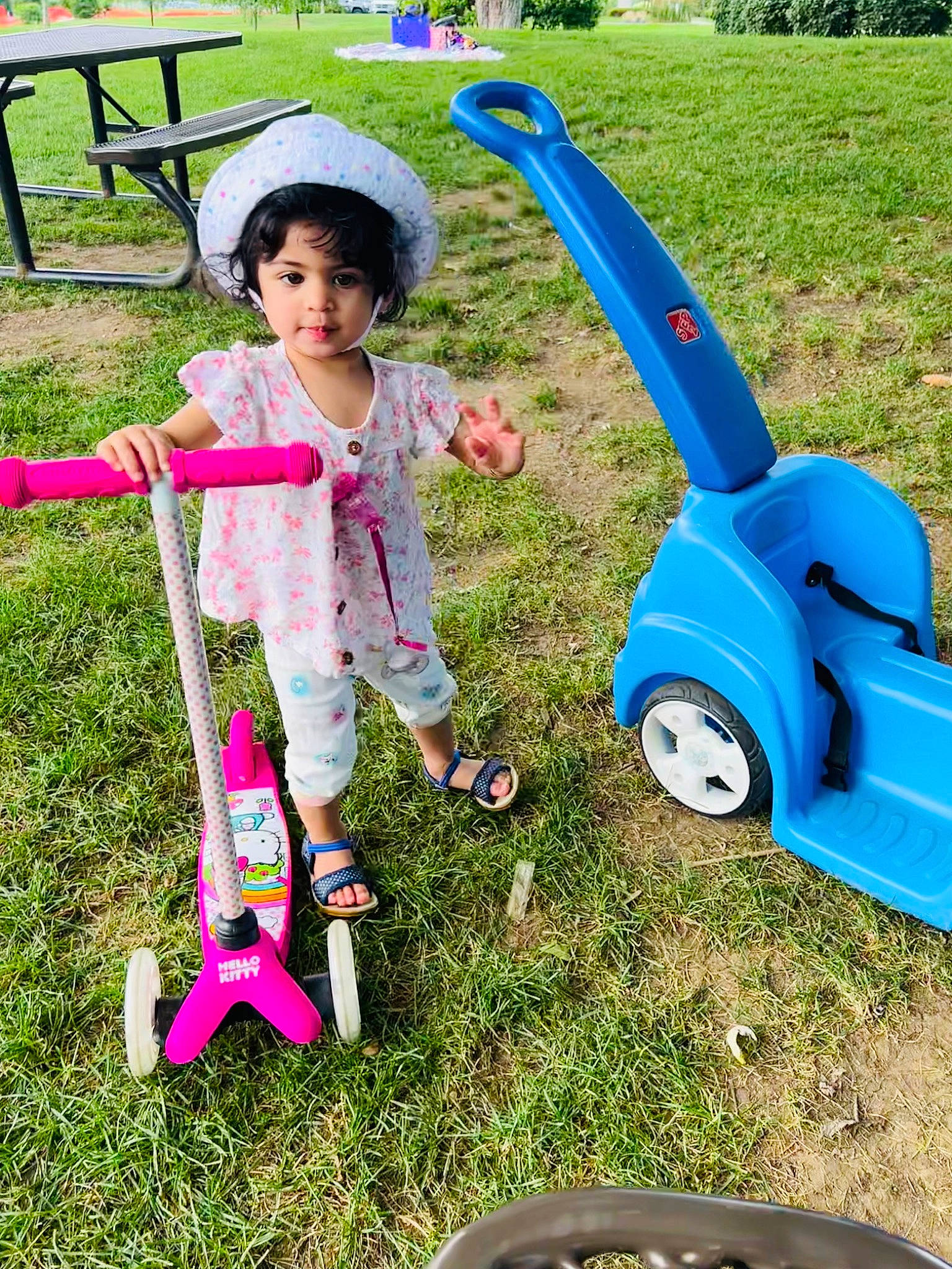 Mia is registered to the contest to win money with this photo: automotive_tire, baby, child, electric_blue, fun, grass, green, lawn, leisure, outdoor_furniture, person, pink, plant, product, public_space, recreation, riding_toy, tire, toddler, vehicle