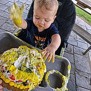 Bray joined the competition — help win amazing prizes! baby, birthday, cake, celebration, child, cream, eating, face, food, frosting, hands, high_chair, messy, outdoor, patio, portrait, smiling, stone_pavers, wooden_bench, yellow