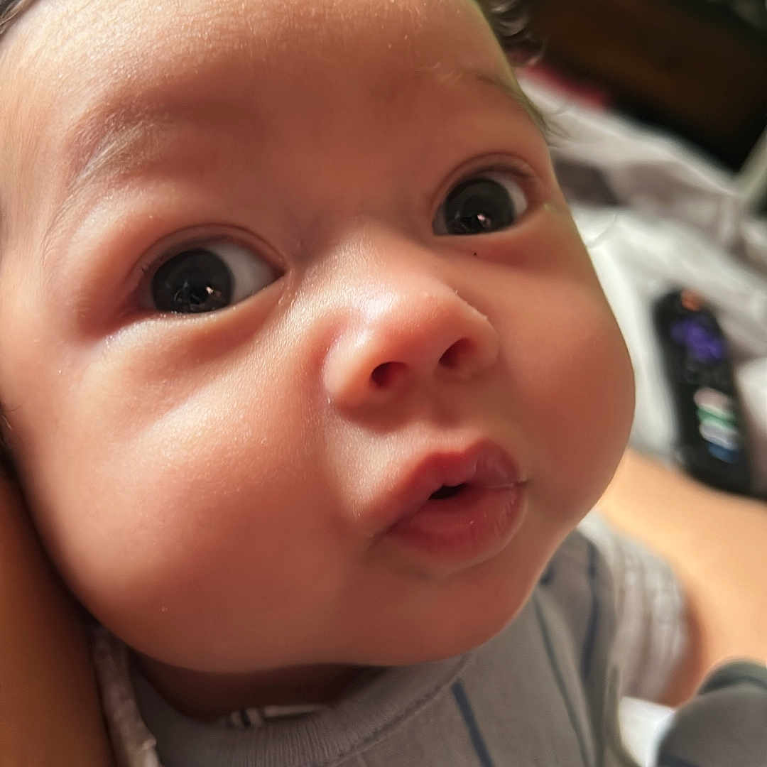 Elijah joined the competition — help win amazing prizes! baby, blue_outfit, chubby_cheeks, closeup, curious, curly_hair, cute, expression, face, head, human, indoor, infant, newborn, person, portrait, skin, soft_lighting, striped_clothing, wide_eyes