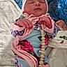 newborn, baby, sleeping, portrait, infant, knit_cap, swaddle, blanket, floral_clothing, pink, blue, pacifier_clip, wooden_beads, face, eyes_closed, hands, indoors, cozy, close_up, candid