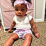 Zayanni joined the competition — help win amazing prizes! baby, child, infant, headband, pink_bow, carpet, indoor, sitting, curious, white_shirt, pink_shorts, furniture, storage_unit, cute, portrait, person, skin, legs, hand, floor