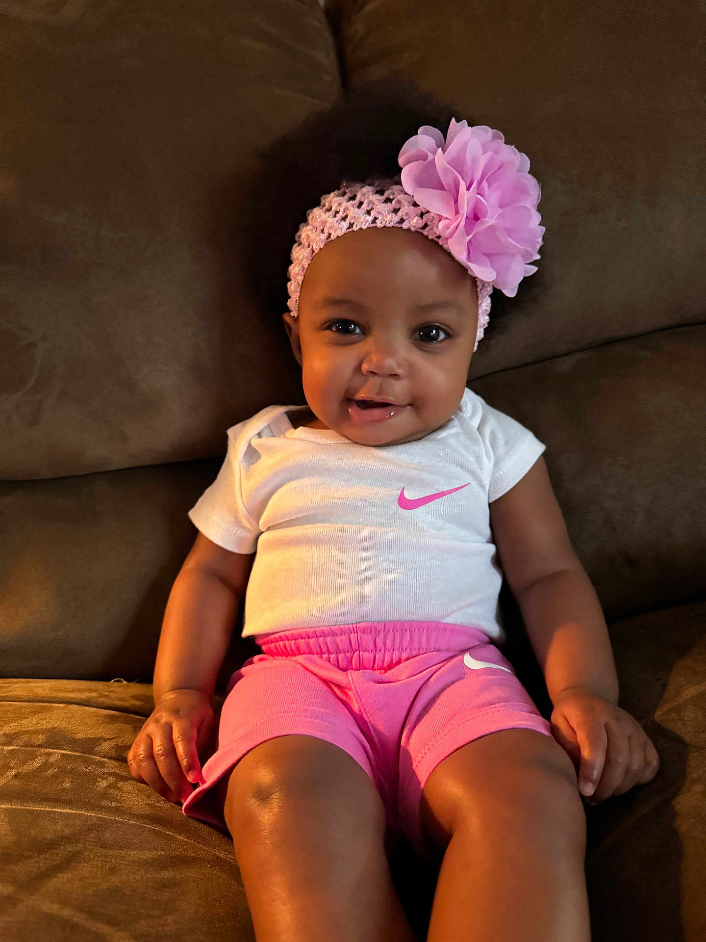 Zayanni joined the competition — help win amazing prizes! baby, child, smiling, headband, flower, pink_shorts, white_shirt, couch, indoor, skin, person, sitting, happy, young_child, cute, clothing, portrait, fashion, relaxed, infant