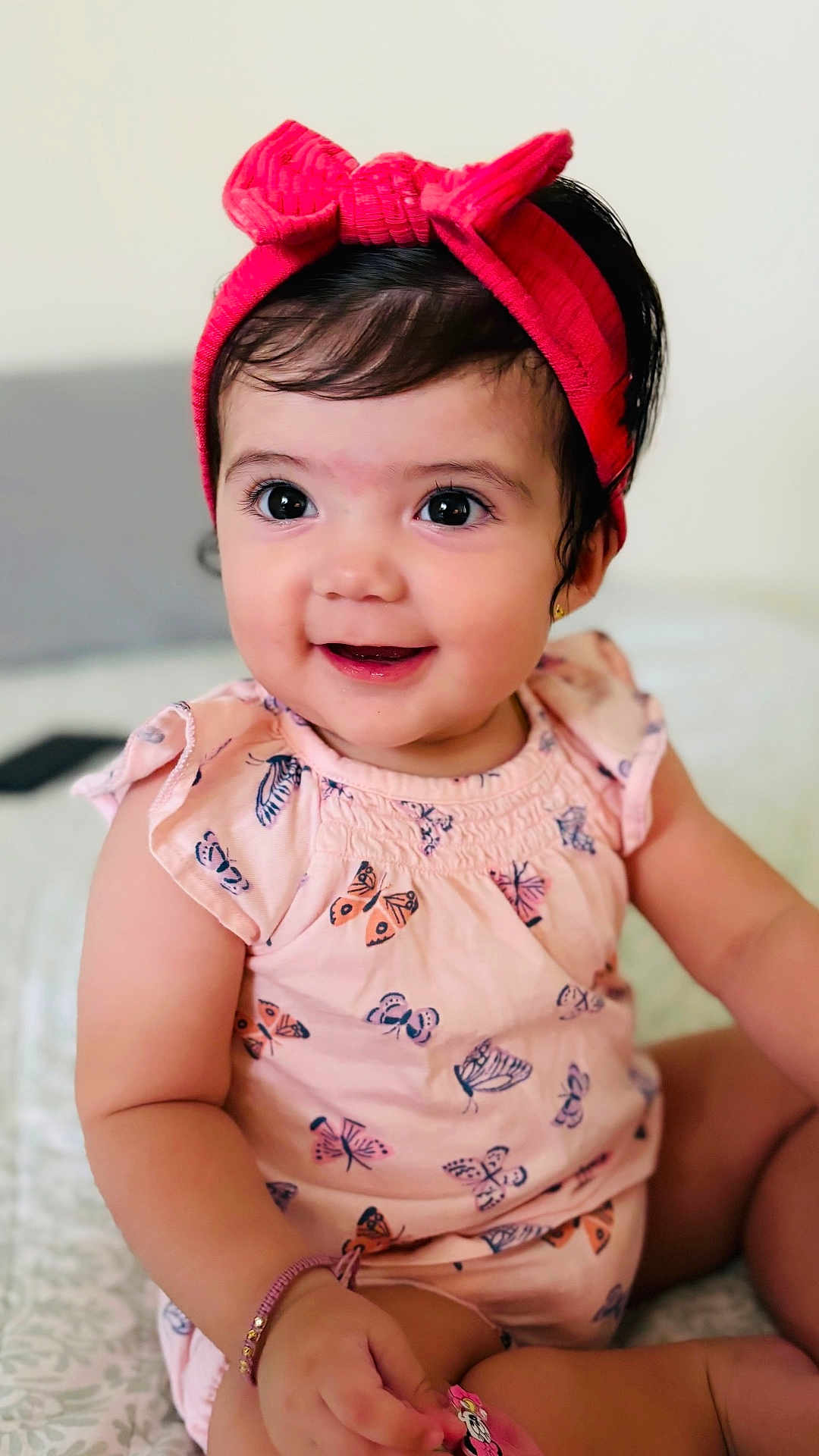 Antonella is registered to the contest to win money with this photo: baby, child, girl, smile, headband, bow, butterfly_pattern, pink_clothing, cute, happy, sitting, bracelet, indoor, portrait, young_child, skin, face, eyes, hand, infant