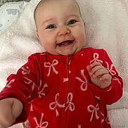 Elaia joined the competition — help win amazing prizes! baby, smiling, red_onesie, bows, blanket, infant, happy, face, lying_down, cheerful, child, cute, soft_texture, indoors, closeup, expression, young, skin, hand, playful