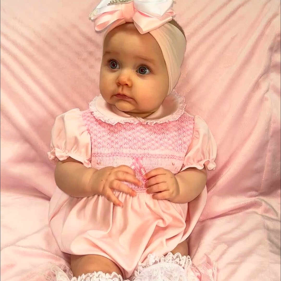 Elaia is registered to the contest to win money with this photo: adorable, baby, blanket, bow, child, chubby_cheeks, clothing, curious, cute, fashion, hands, headband, indoor, infant, lace_socks, pink_dress, portrait, sitting, soft_texture, young