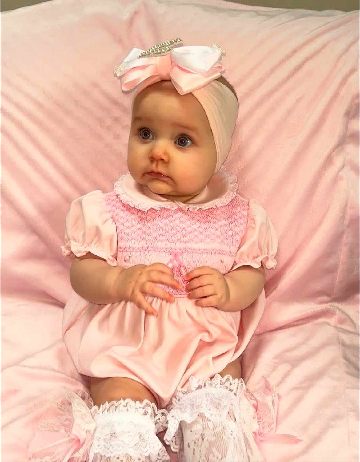 Elaia is registered to the contest to win money with this photo: baby, infant, pink_dress, headband, bow, cute, child, soft_texture, blanket, sitting, portrait, lace_socks, adorable, indoor, young, chubby_cheeks, curious, fashion, clothing, hands
