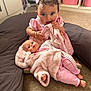 Gabriella joined the competition — help win amazing prizes! toddler, child, baby_doll, pink_dress, bow, blanket, cushion, carpet, indoor, toy, playtime, cute, curly_hair, storage_bins, room, floor, soft_texture, infant, holding, chewing