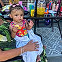 Gabriella joined the competition — help win amazing prizes! toddler, child, person, adult, towel, food, chip, outdoor, table, drink, bottle, brick_wall, glass_table, chair, clothing, hand, foot, toy, cup, sunlight