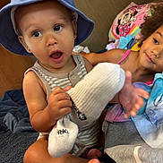 Ceazyn is registered to the contest to win money with this photo: baby, child, toddler, siblings, portrait, smiling, surprised, sun_hat, bottle, feeding, indoor, seated, close_up, faces, brown_skin, curly_hair, striped_clothing, pink_clothing, blanket, family