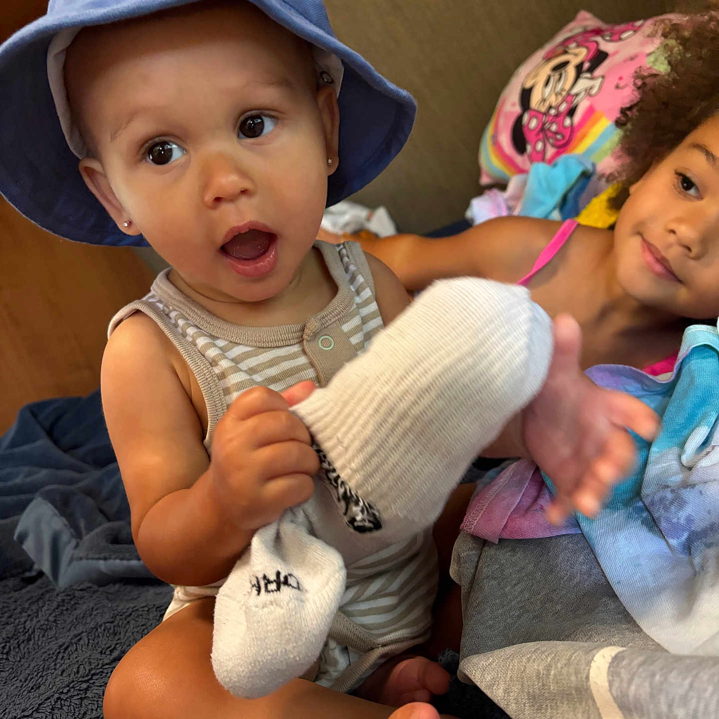 Ceazyn is registered to the contest to win money with this photo: baby, child, toddler, siblings, portrait, smiling, surprised, sun_hat, bottle, feeding, indoor, seated, close_up, faces, brown_skin, curly_hair, striped_clothing, pink_clothing, blanket, family