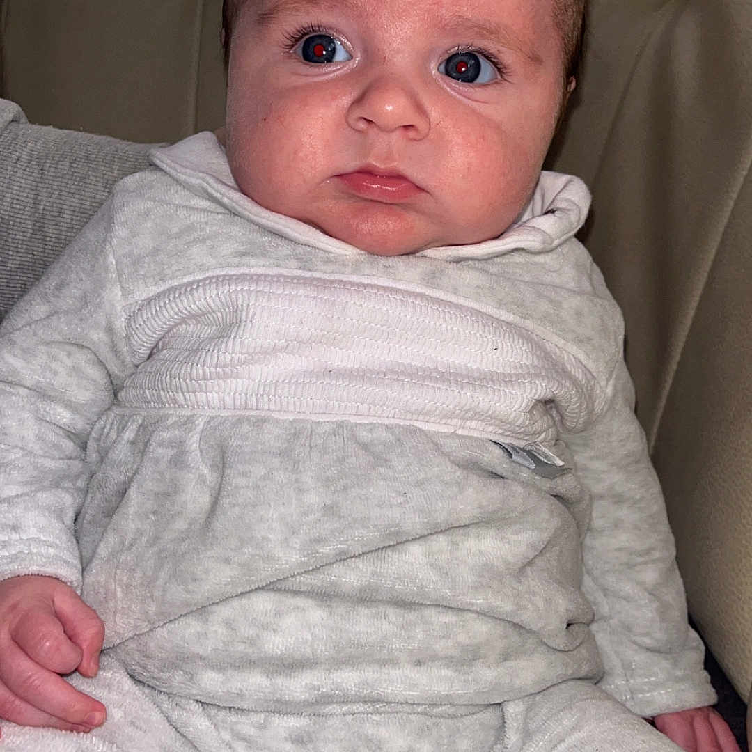 Elie participe au concours pour gagner de l'argent avec cette photo : baby, child, clothing, cute, expression, eyes, face, furrowed_brow, hands, indoors, infant, leather_seat, legs, pajamas, person, portrait, seated, skin, sleeves, young