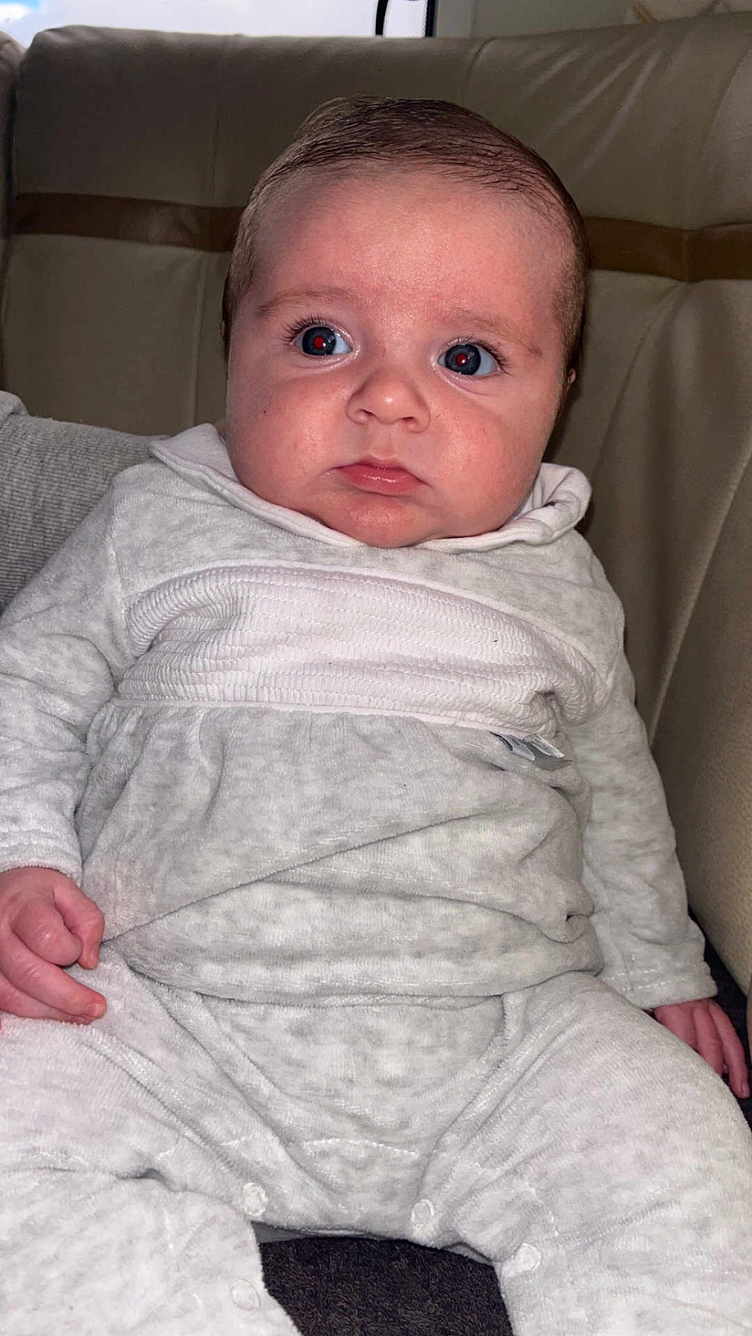 Elie participe au concours pour gagner de l'argent avec cette photo : baby, infant, child, face, eyes, hands, clothing, pajamas, seated, leather_seat, indoors, portrait, cute, young, person, skin, expression, sleeves, legs, furrowed_brow
