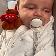 Elie participe au concours pour gagner de l'argent avec cette photo : baby, sleeping, pacifier, plush_toy, teddy_bear, onesie, white_clothing, infant, cute, cozy, peaceful, child, face, soft_toy, resting, indoor, closeup, comfort, adorable, baby_sleeping