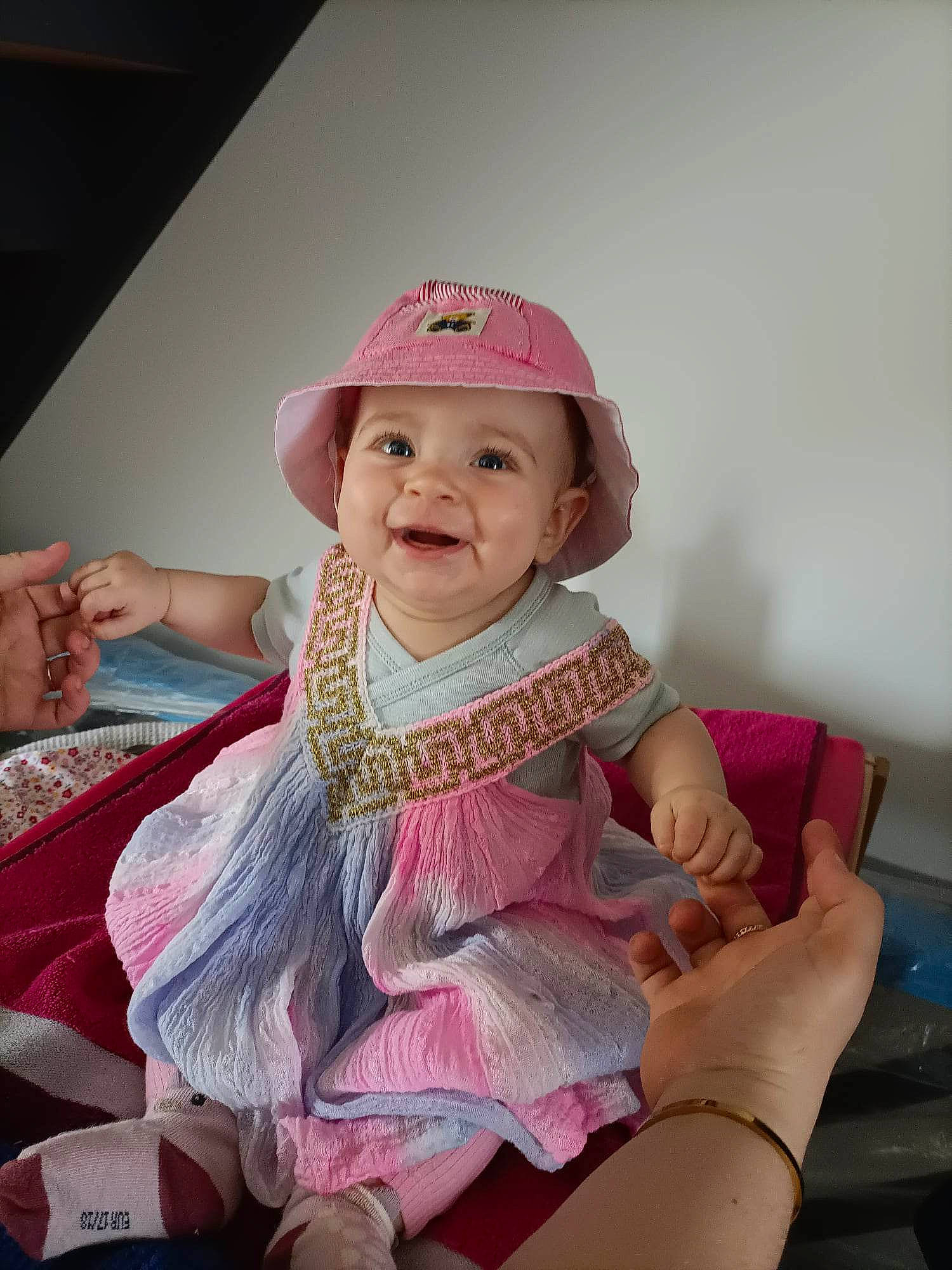 Eva a rejoint le concours — aidez-le/la à gagner de superbes lots ! baby, baby_toddler_clothing, cap, child, dress, face, fashion_accessory, fun, hand, happy, hat, headgear, headwear, jewellery, joy, magenta, person, pink, purple, skin