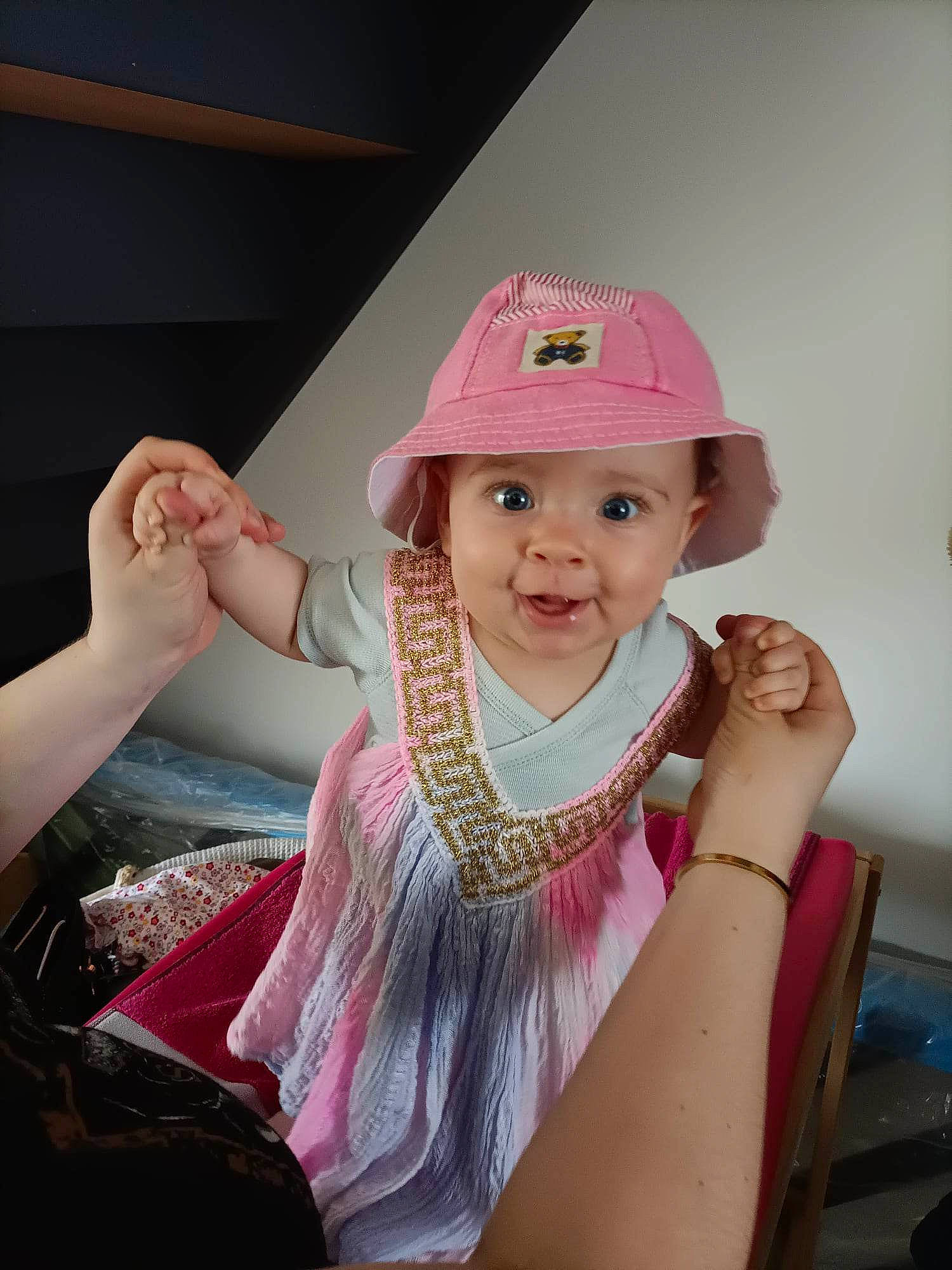 Eva participe au concours pour gagner de l'argent avec cette photo : baby, baby_toddler_clothing, baseball_cap, cap, child, fashion_accessory, fun, gesture, hair_accessory, hand, happy, hat, headgear, headwear, leisure, magenta, person, pink, sitting, sleeve