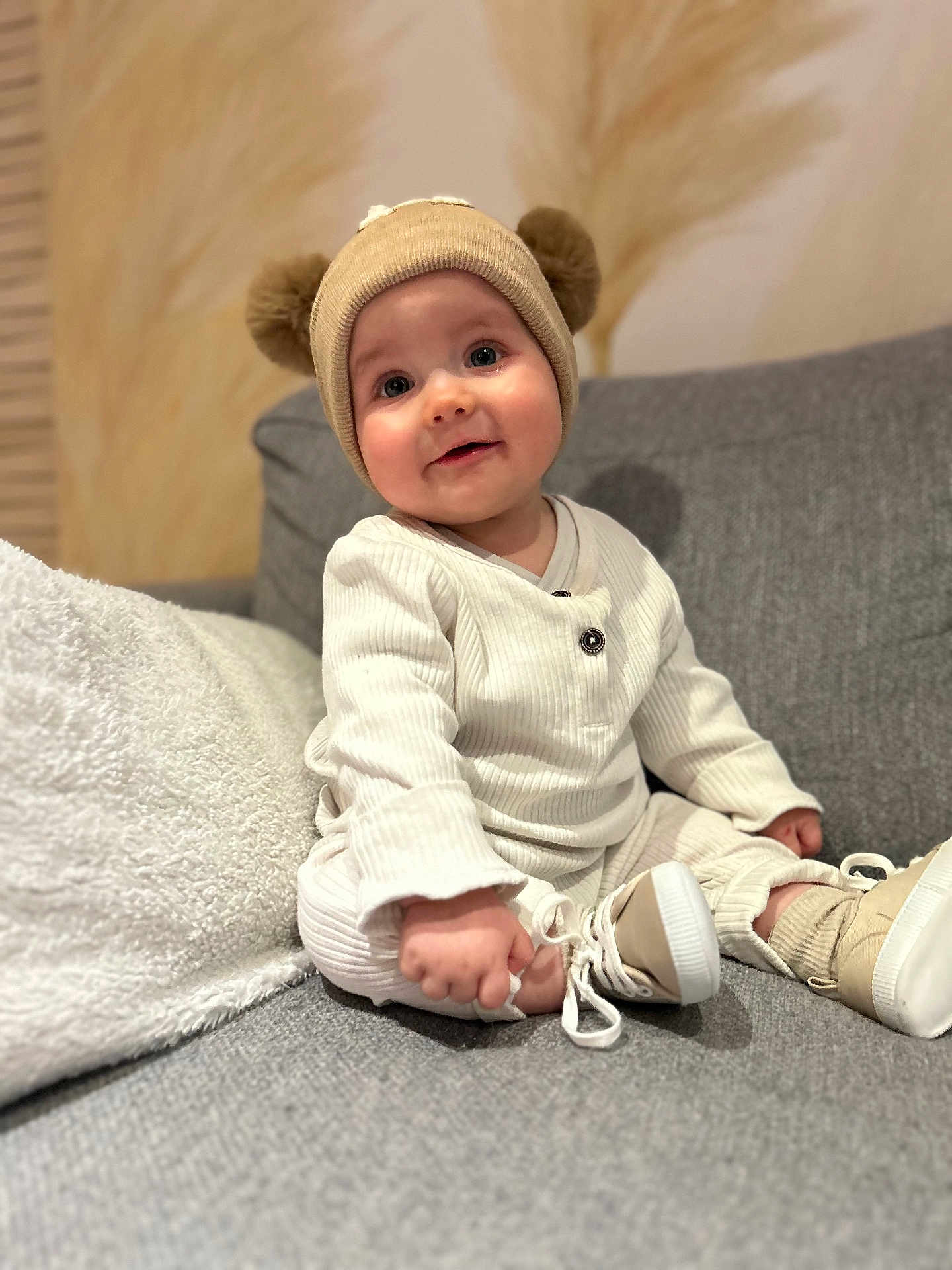 Marceau a rejoint le concours — aidez-le/la à gagner de superbes lots ! baby, child, hat, pom_poms, beige, cream, couch, gray, shoes, socks, smile, face, person, indoors, soft_texture, warm_lighting, clothing, seated, cute, portrait