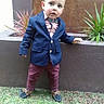 child, toddler, boy, portrait, outdoor, standing, formal_wear, suit, blazer, bow_tie, dress_shirt, trousers, loafers, plants, planter, garden, grass, wooden_background, full_body, fashion