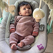 Rose participe au concours pour gagner de l'argent avec cette photo : baby, infant, baby_rocker, knit_clothing, plush_toy, pacifier, floor_tile, indoor, child, cute, soft_lighting, seat, baby_girl, baby_boy, hands, feet, looking_up, baby_accessory, comfort, home